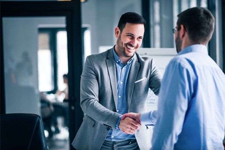 Two people shaking hands in an office setting.