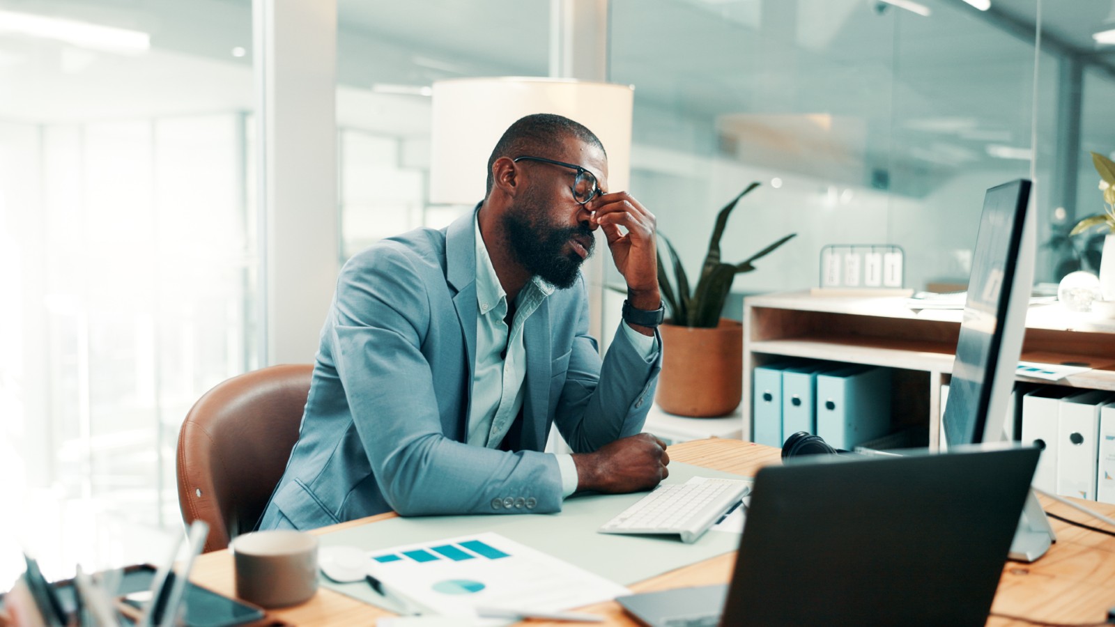 Stress, headache and black man in office with fatigue, mistake or brain fog for finance report. Glasses, exhaustion and African male financial advisor with migraine for error in investment proposal.